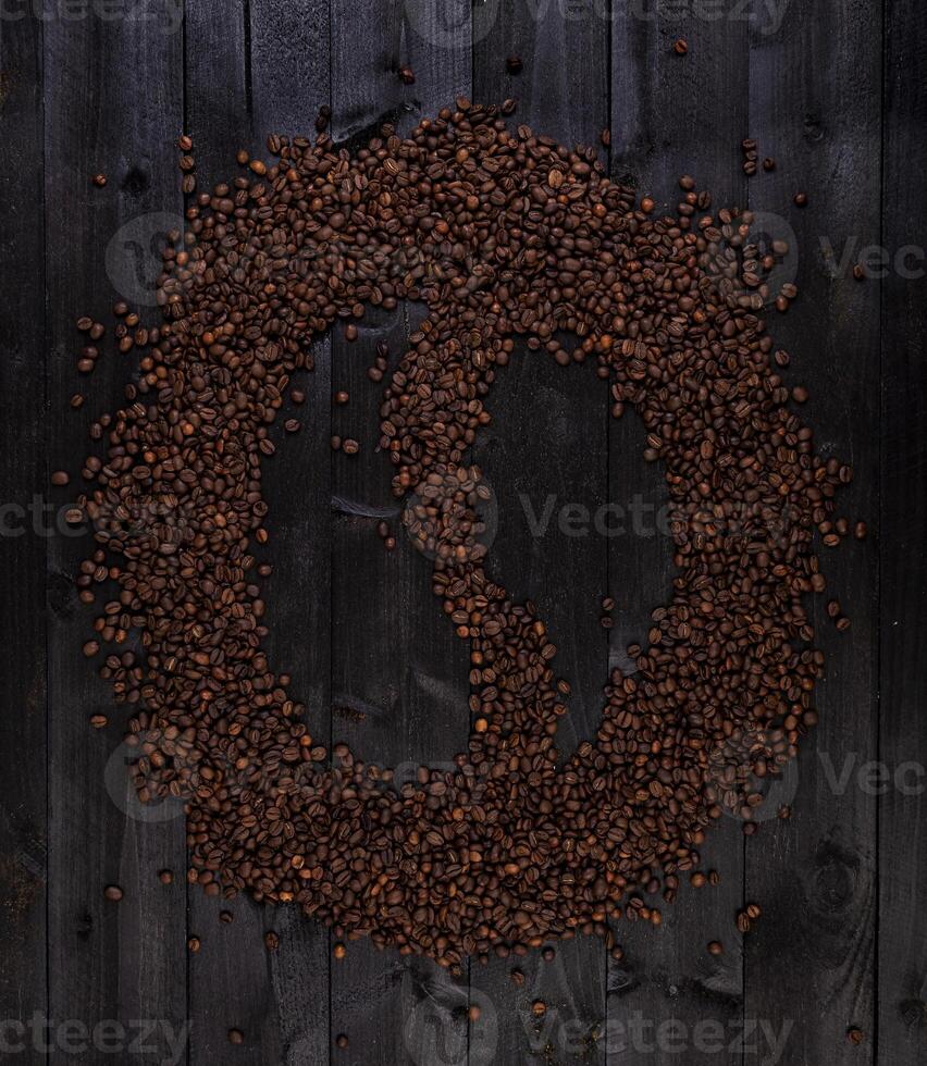 kaffe symbol tillverkad av rostad kaffe bönor på en svart trä- bakgrund foto