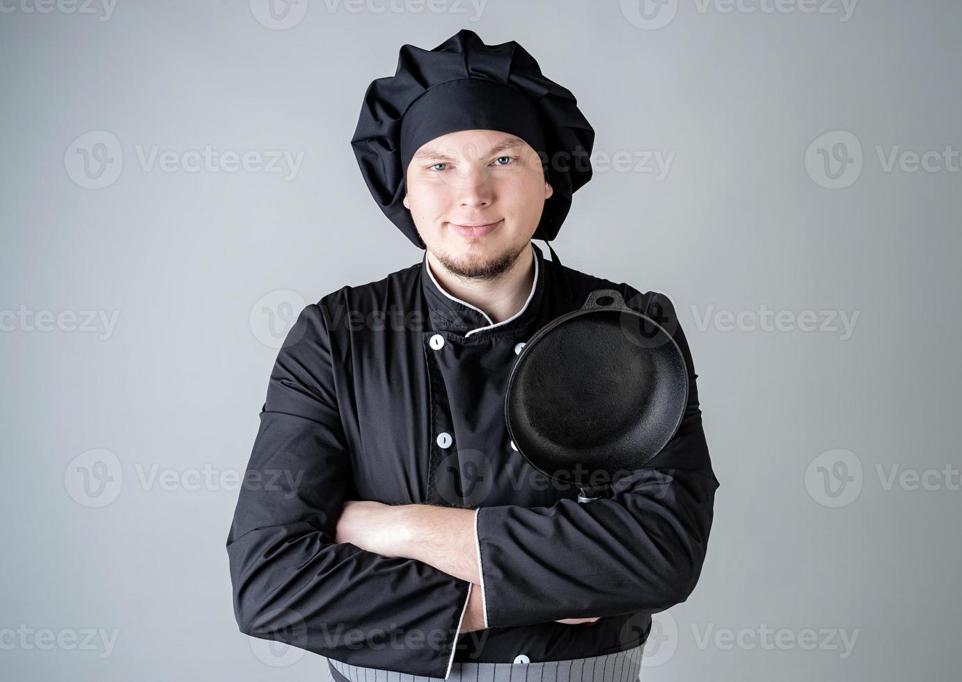 manlig kock som håller en kastrull isolerad på grå bakgrund foto