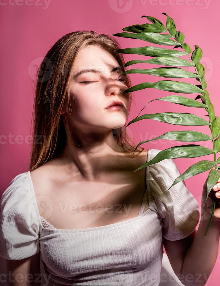 ung vacker kvinna med slutna ögon med ett palmblad foto