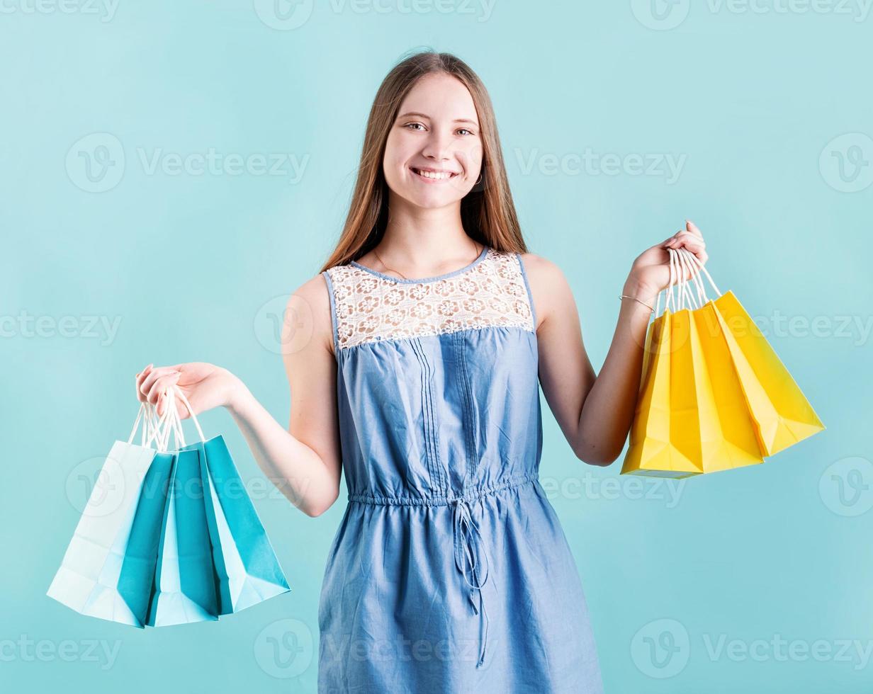 glad ung kvinna med shoppingkassar isolerad på blå bakgrund foto