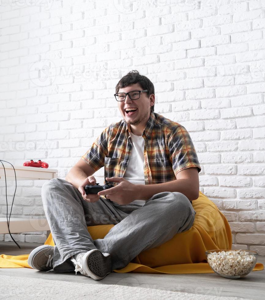 upphetsad ung man spelar tv-spel hemma och skrattar foto
