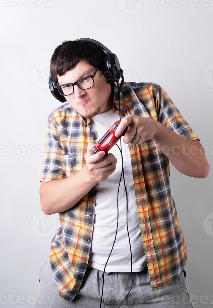 rolig ung man spelar videospel som håller en joystick isolerad på grå bakgrund foto