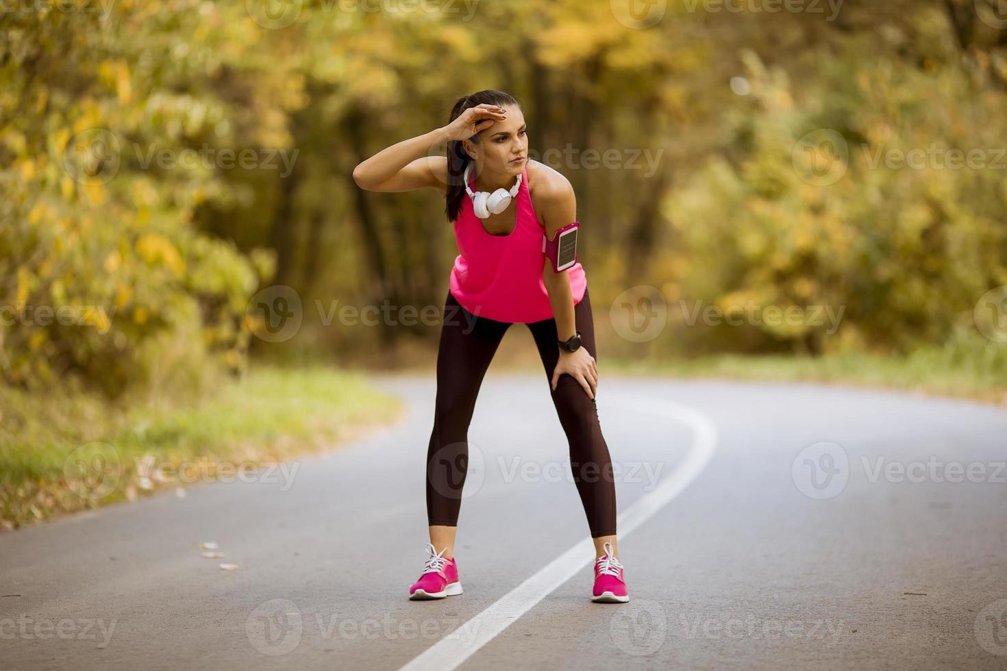 ung kvinna har en paus under träning i höstskogen foto