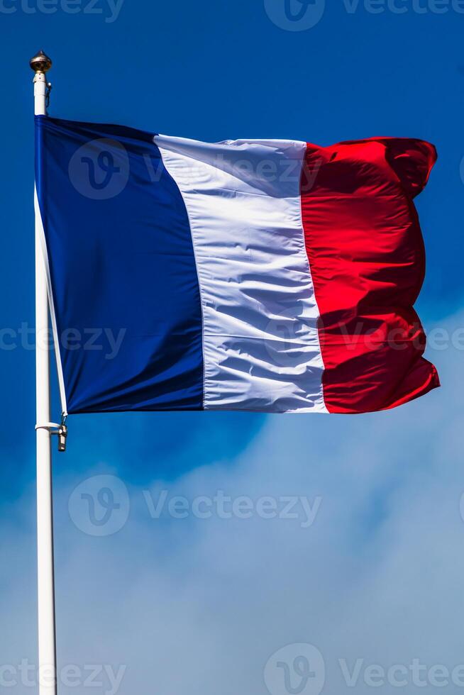 franska tricolor flagga fladdrande med stark vind och blå himmel foto