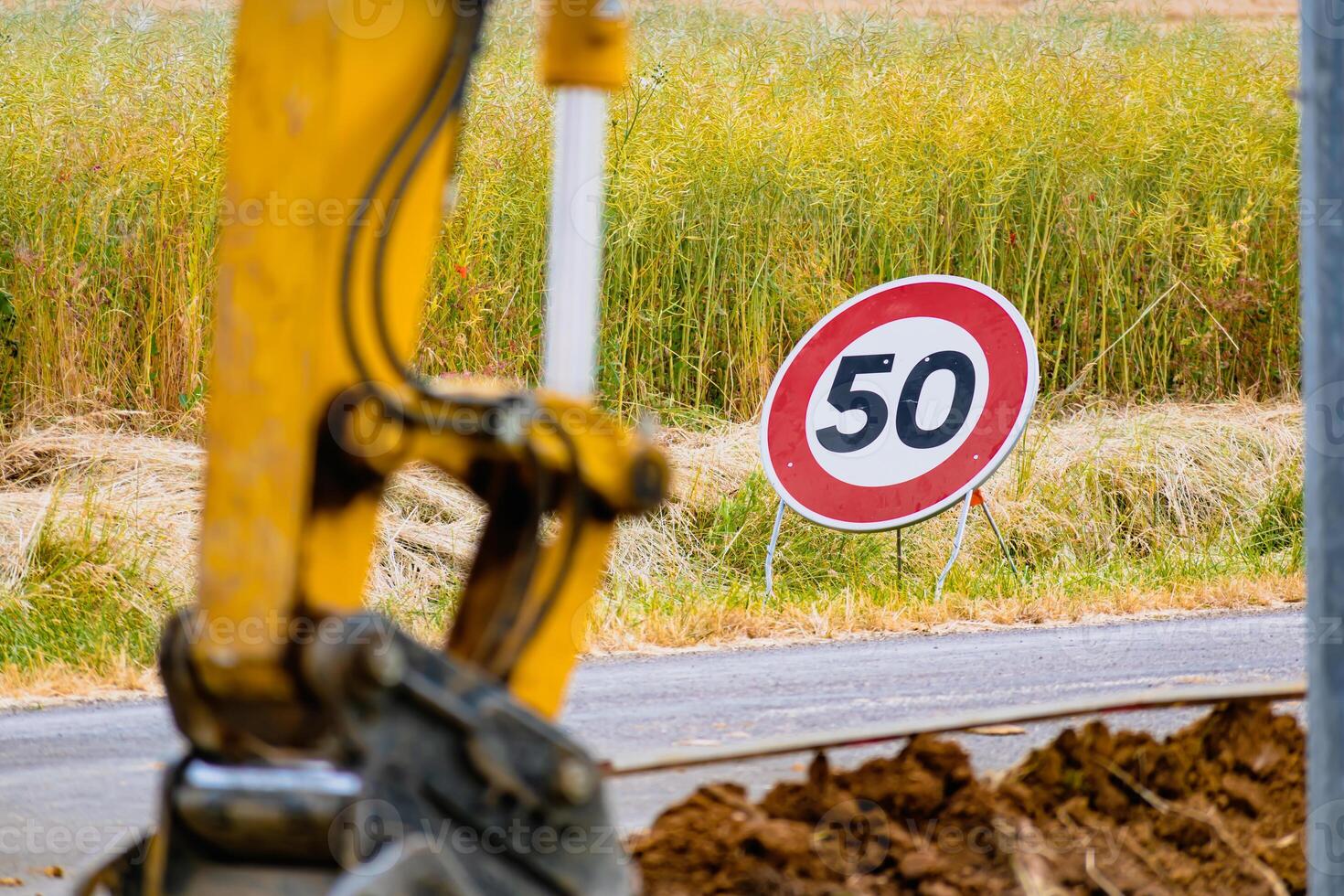 ärm av en mini grävare och hink med en hastighet begränsa tecken på 50, väg tecken foto