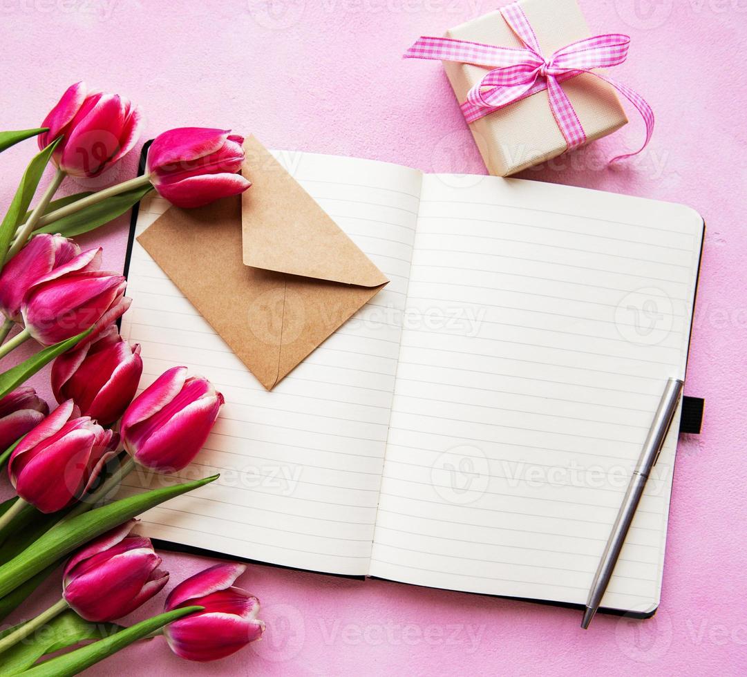 anteckningsbok, presentförpackning och rosa tulpaner foto