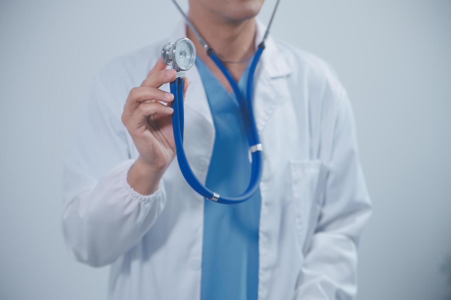 senior läkare bär vit täcka stående innehav stetoskop i händer. äldre manlig läkare sjukvård professionell som visar medicinsk Utrustning redo till lyssna lungor eller hjärta begrepp. stänga upp se foto