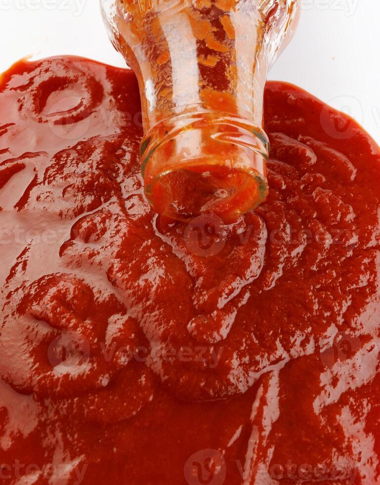 tomat sås . glas flaska med ketchup. ketchup är häller ut av de nacke av en glas flaska. foto