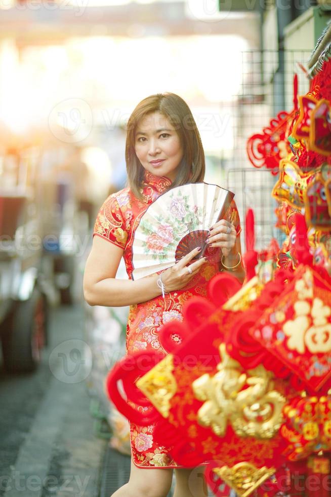 asiatisk kvinna som bär kinesiska traditionskläder med kinesisk bambufläkt tandigt leende ansikte på yaowarat street, Kina, Bangkok, Thailand foto