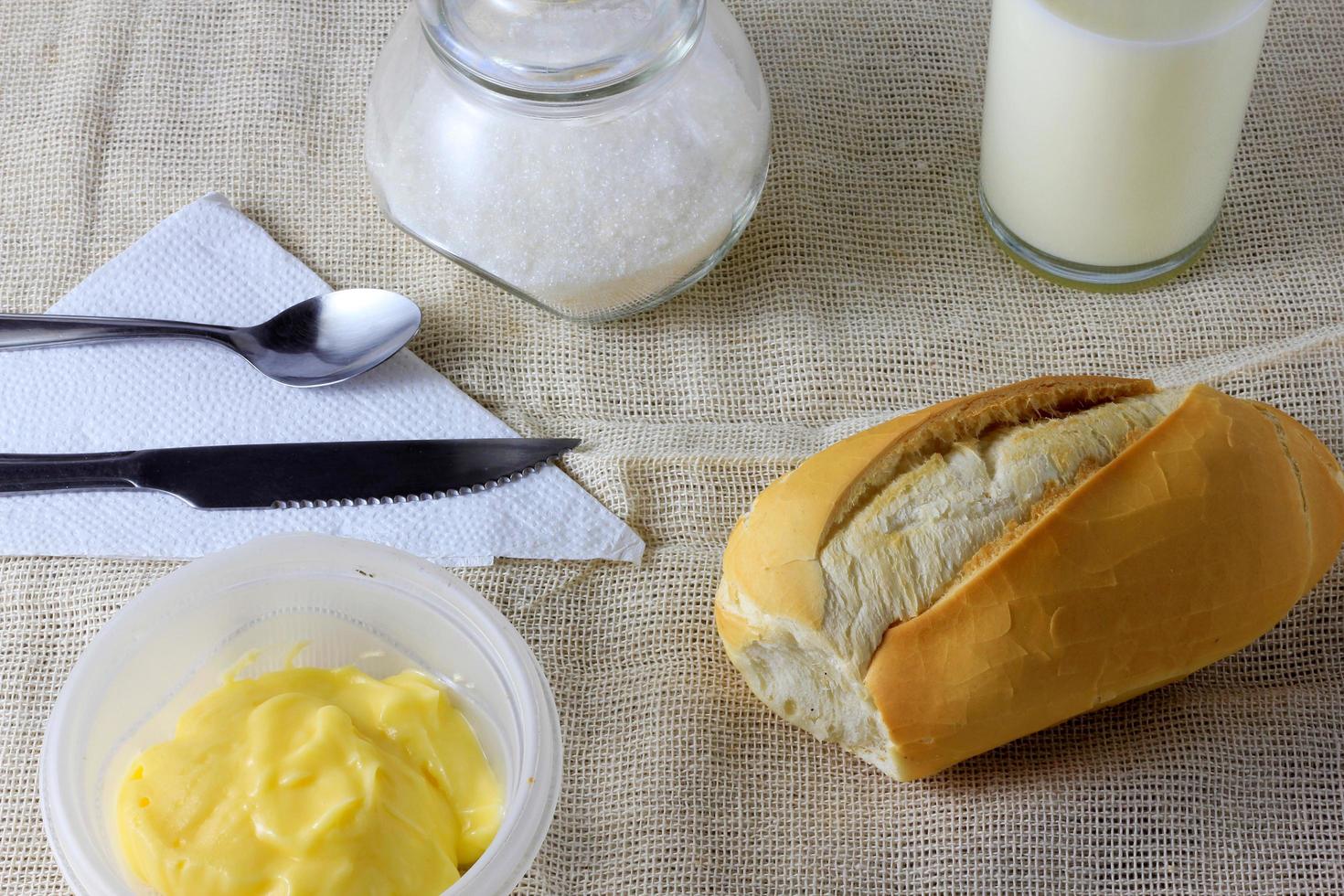 närbild franskt bröd på trä frukostbord med smör och bestick foto