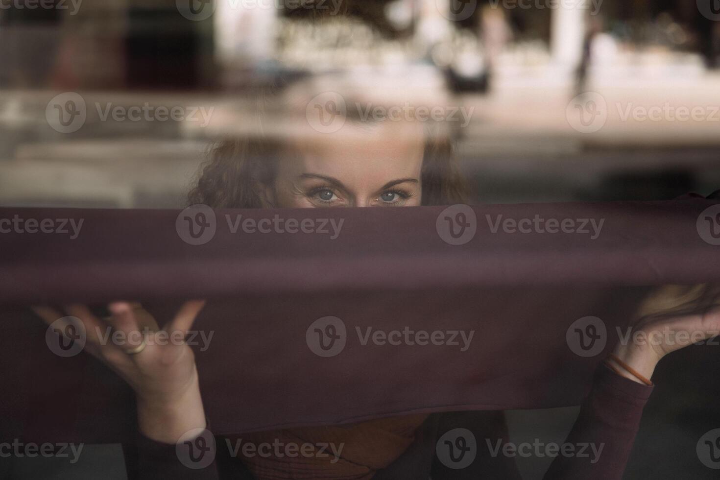 nyfiken kvinna peering genom reflekterande glas fönster i urban miljö foto