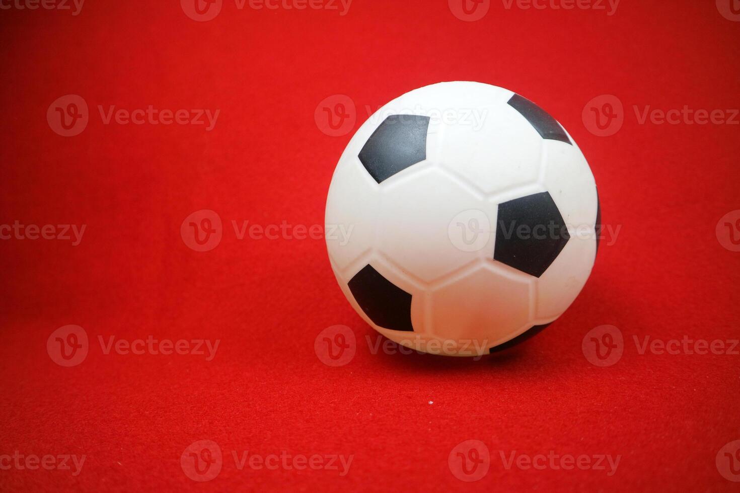en små vit och svart leksak sudd boll. röd bakgrund foto
