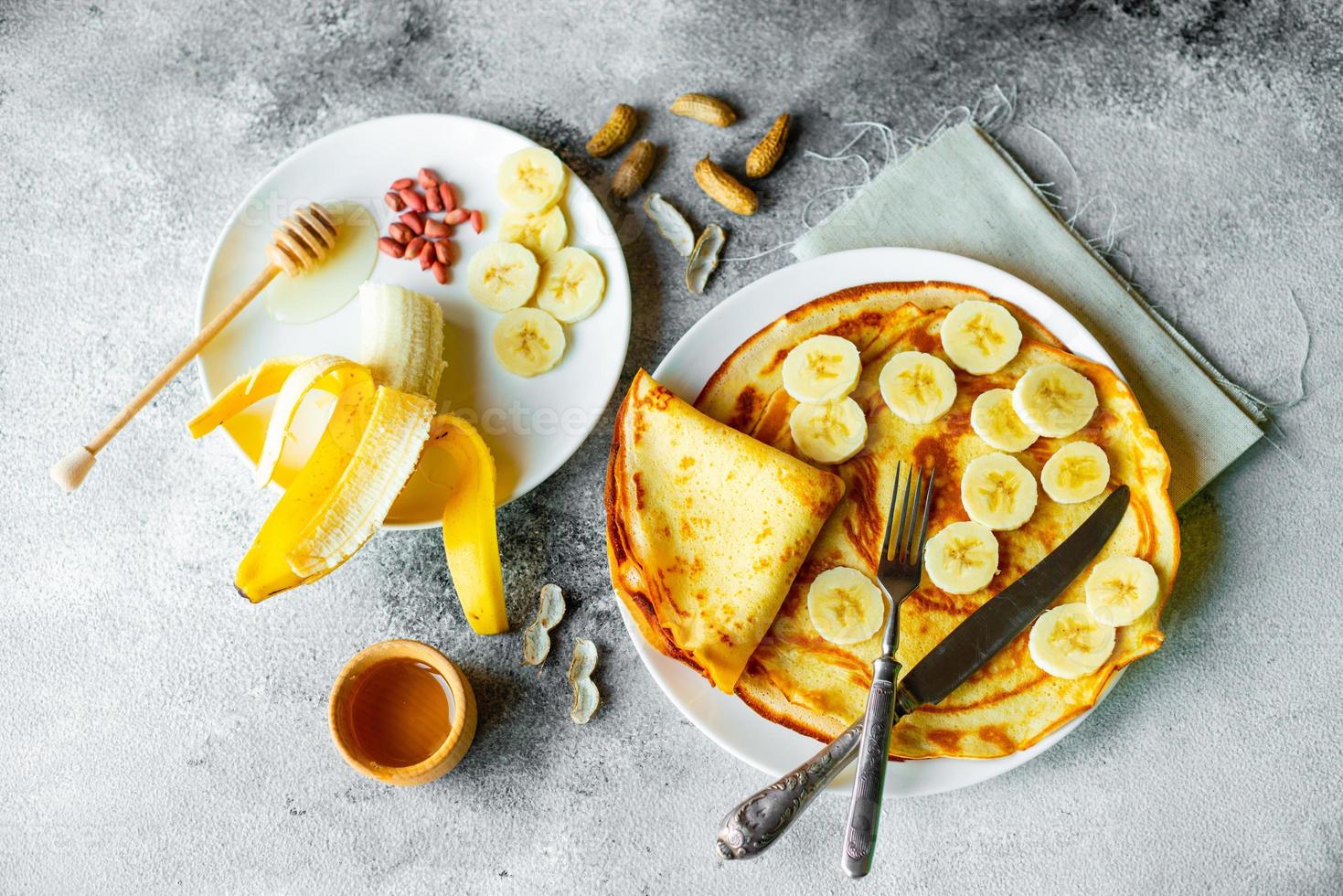 läckra vackra pannkakor med banan och honung på en konkret bakgrund foto