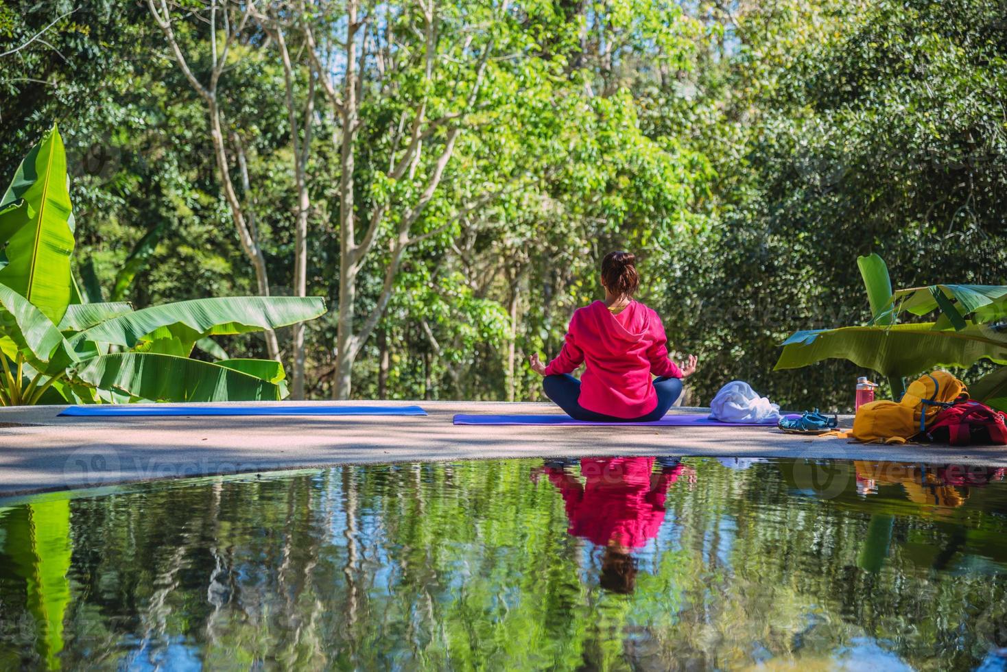 asiatisk kvinna reser naturen. resa slappna av. yogaställning fitnessställ på poolen. foto