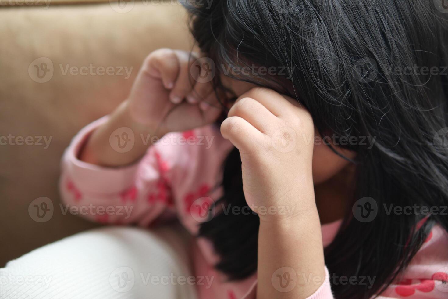 en upprörd barn flicka omslag henne ansikte med hand foto