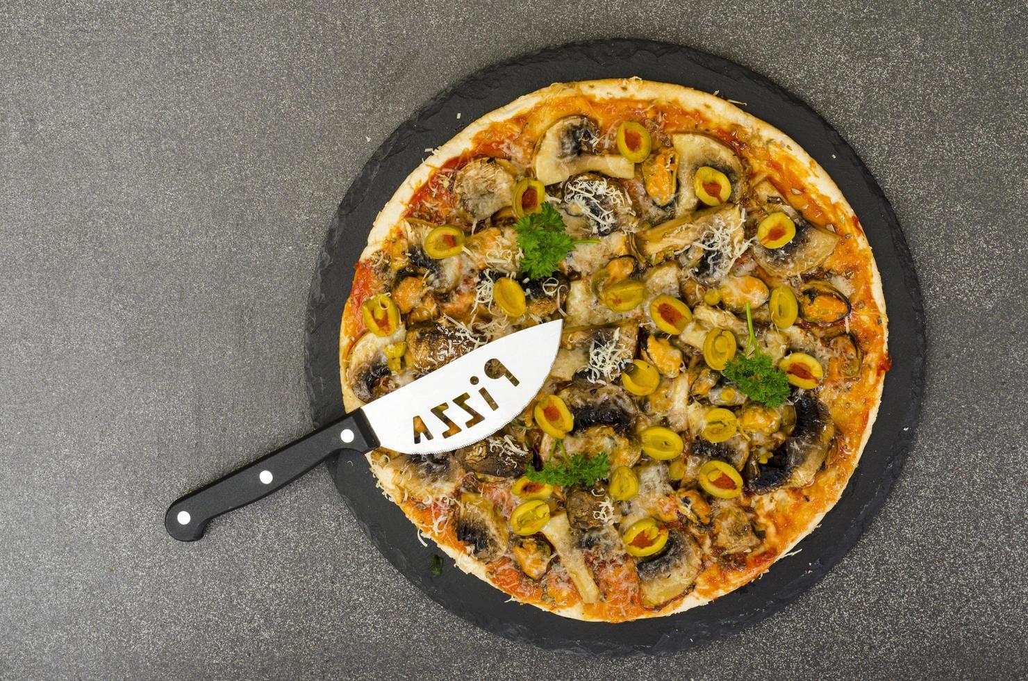 pizza med musslor, champinjoner, gröna oliver. studiofoto foto