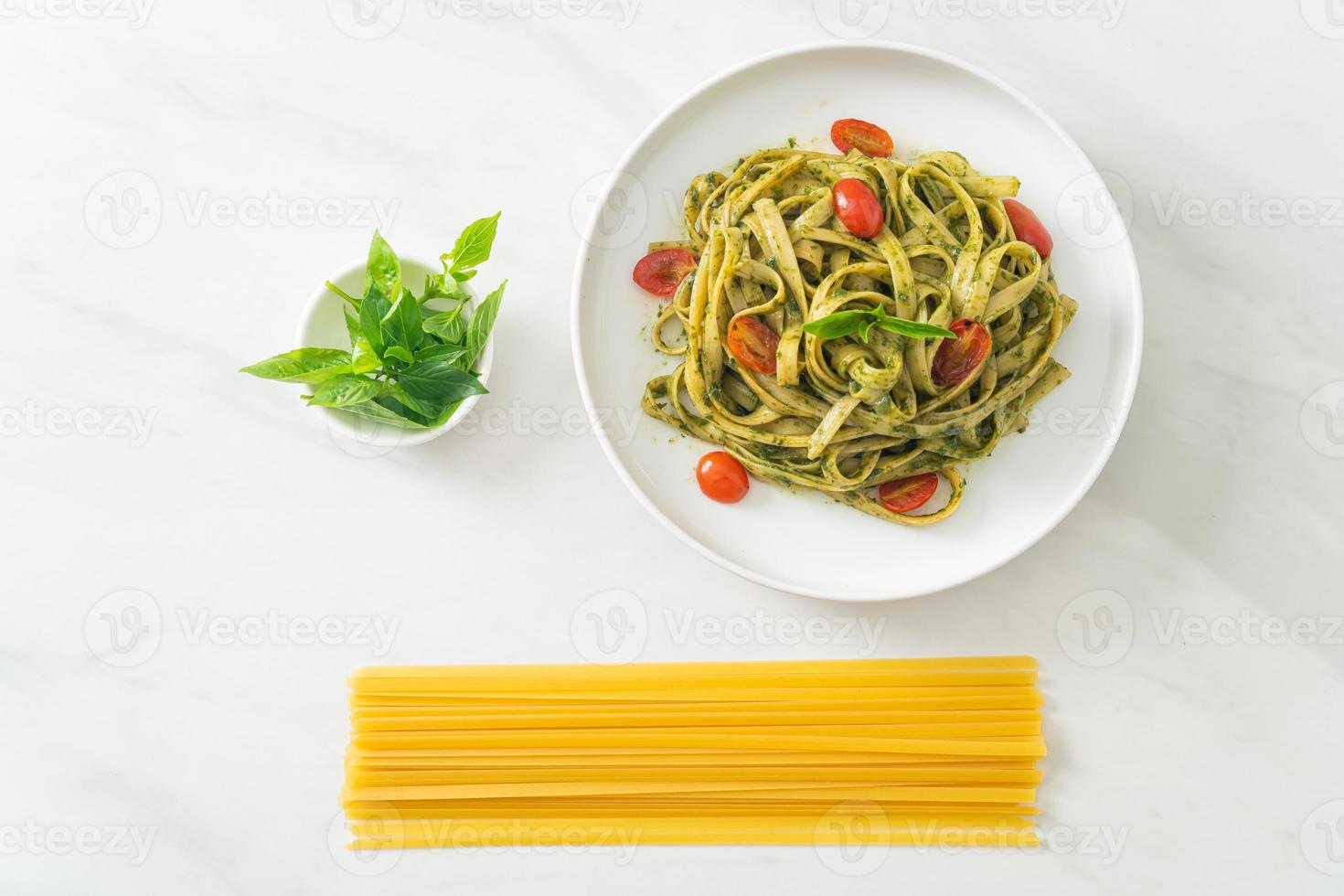 fettuccine spaghetti pasta med pestosås och tomater foto