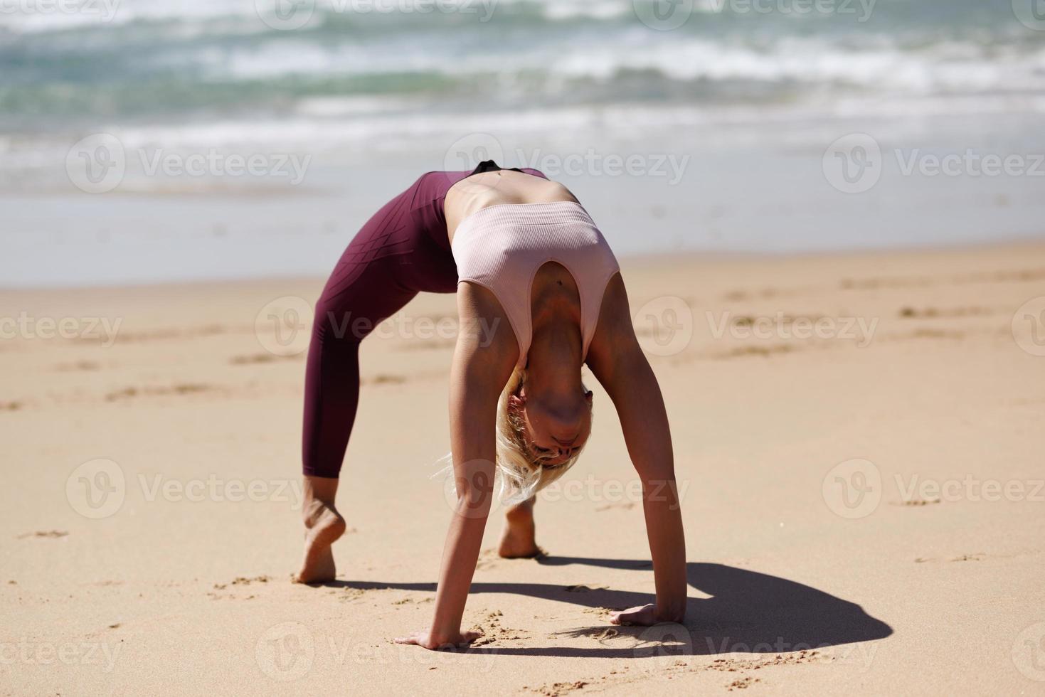 kaukasisk blond kvinna utövar yoga på stranden foto