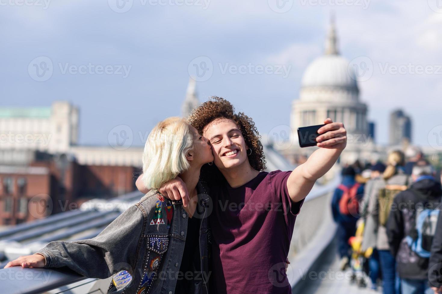 lyckligt par som tar ett selfiefotografi på londons millennium bridge foto