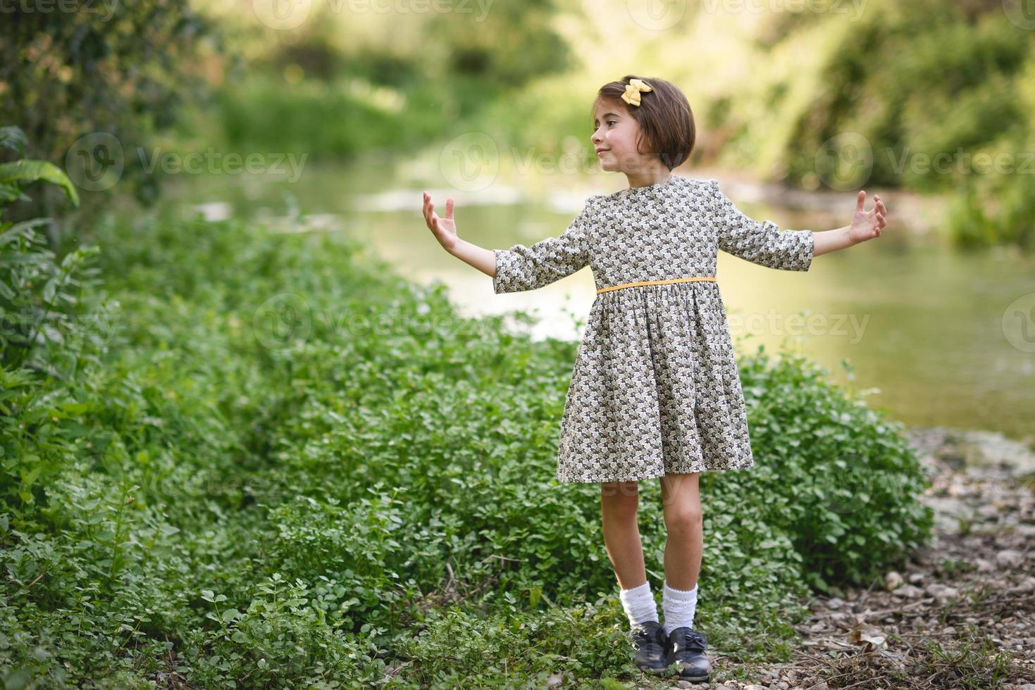 liten flicka i naturen ström bär vacker klänning foto