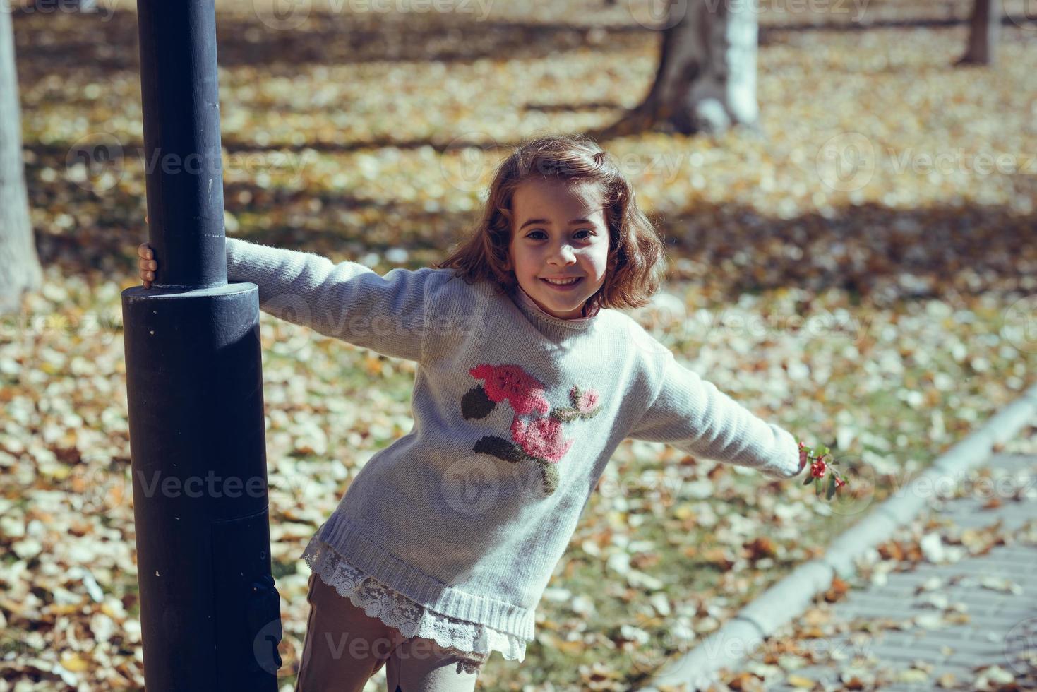 liten flicka som leker i en stadspark på hösten foto
