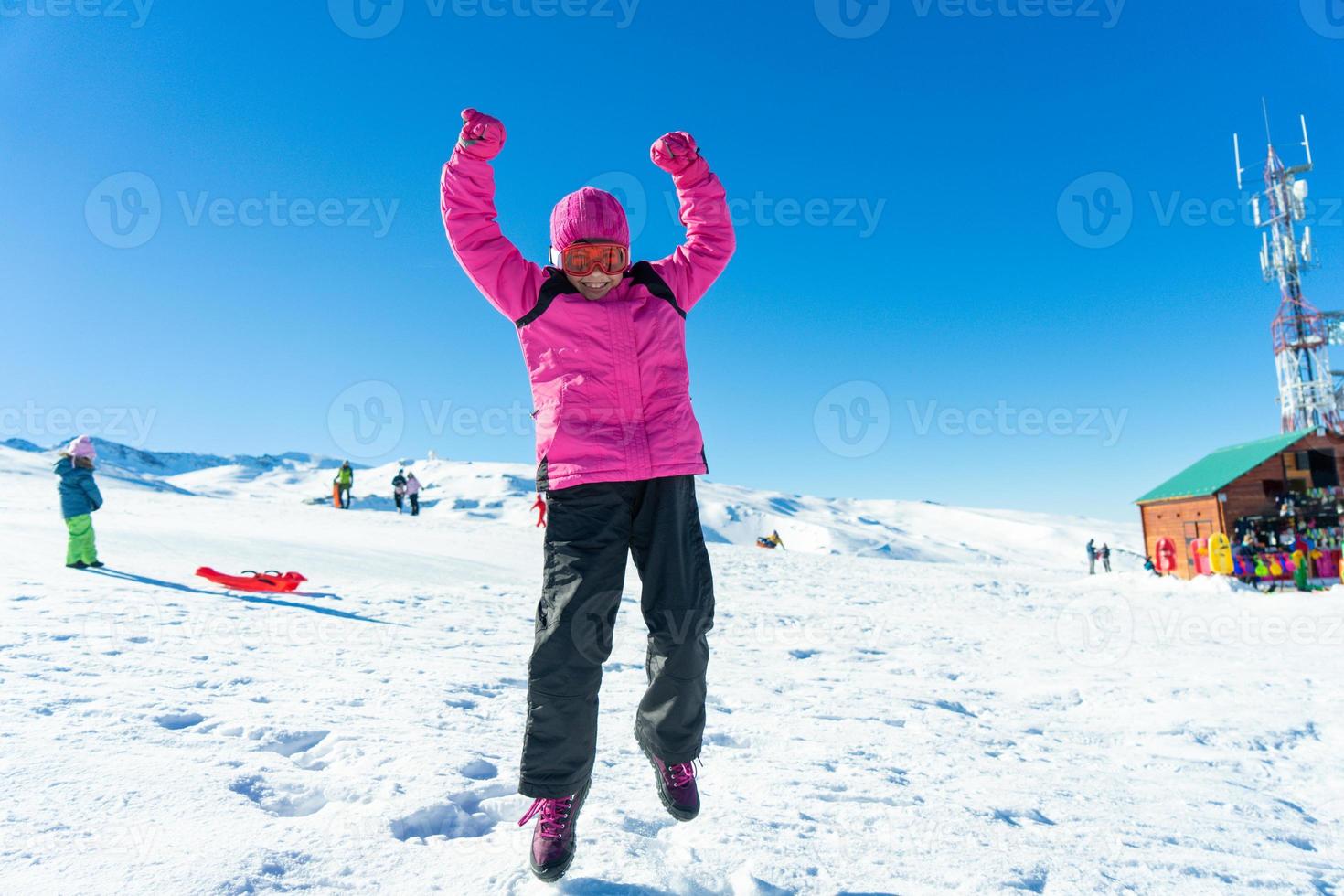 liten flicka hoppar på snön på Sierra Nevada skidort. foto
