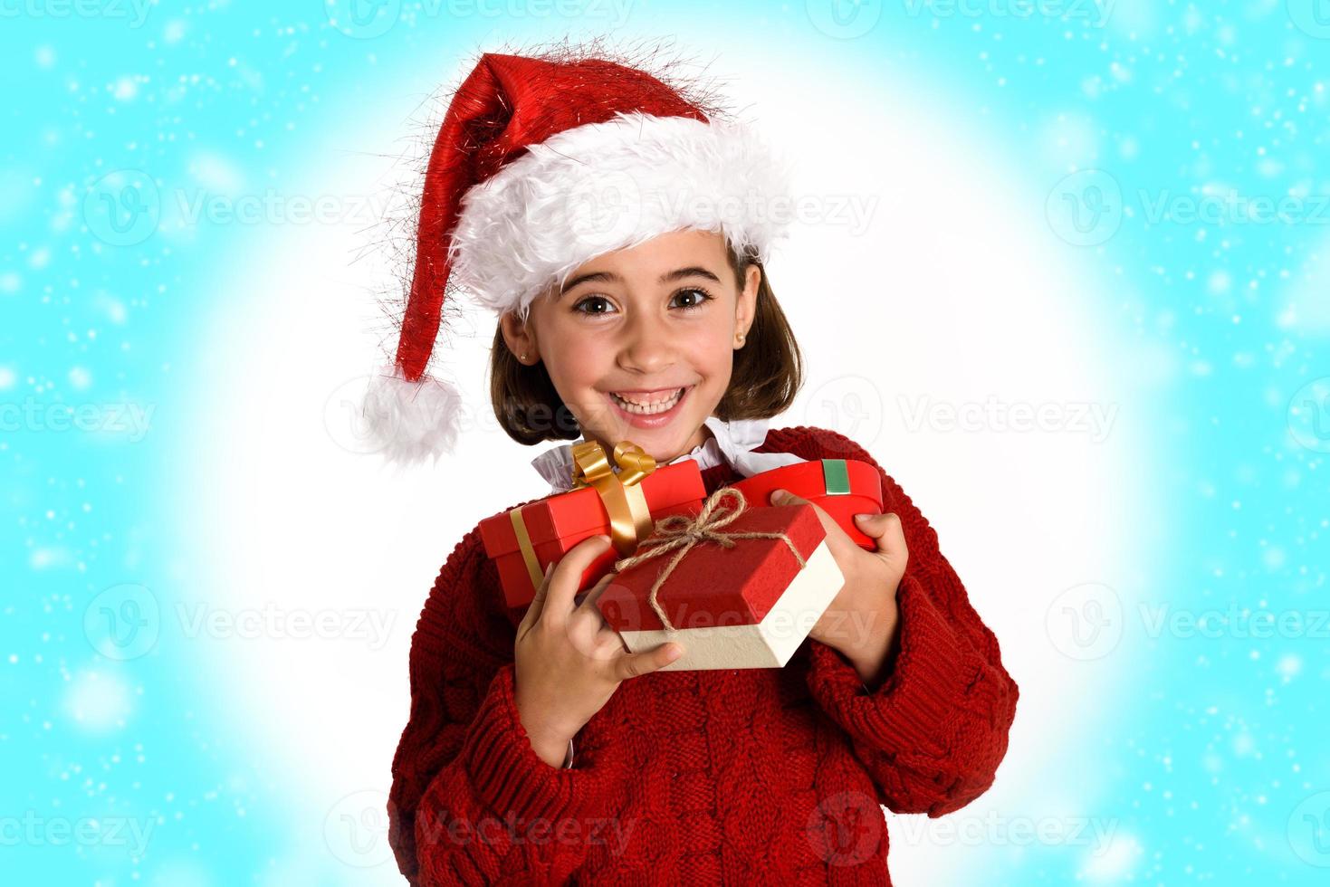 liten flicka som bär tomtehatt som bär många presentförpackningar foto