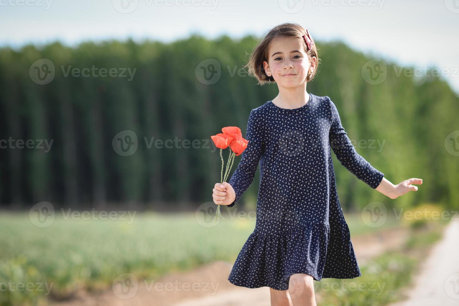 liten flicka går i naturfältet bär vacker klänning foto