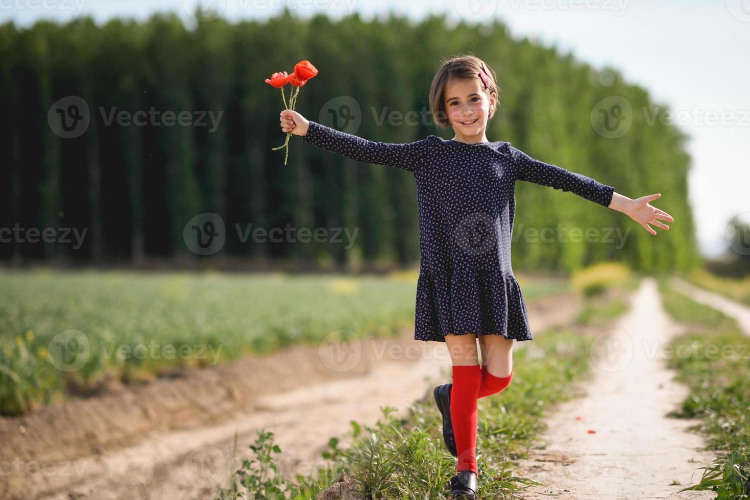 liten flicka går i naturfältet bär vacker klänning foto