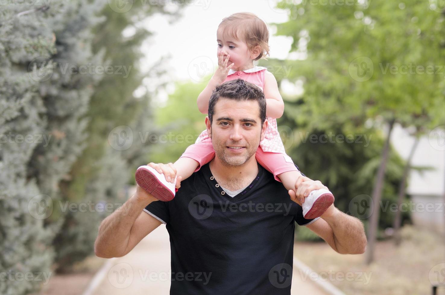 liten flicka som går på sin fars axlar foto