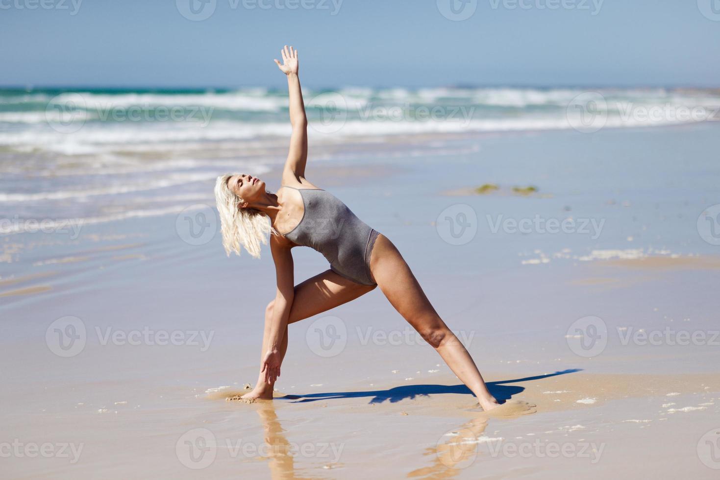 kaukasisk blond kvinna utövar yoga på stranden foto