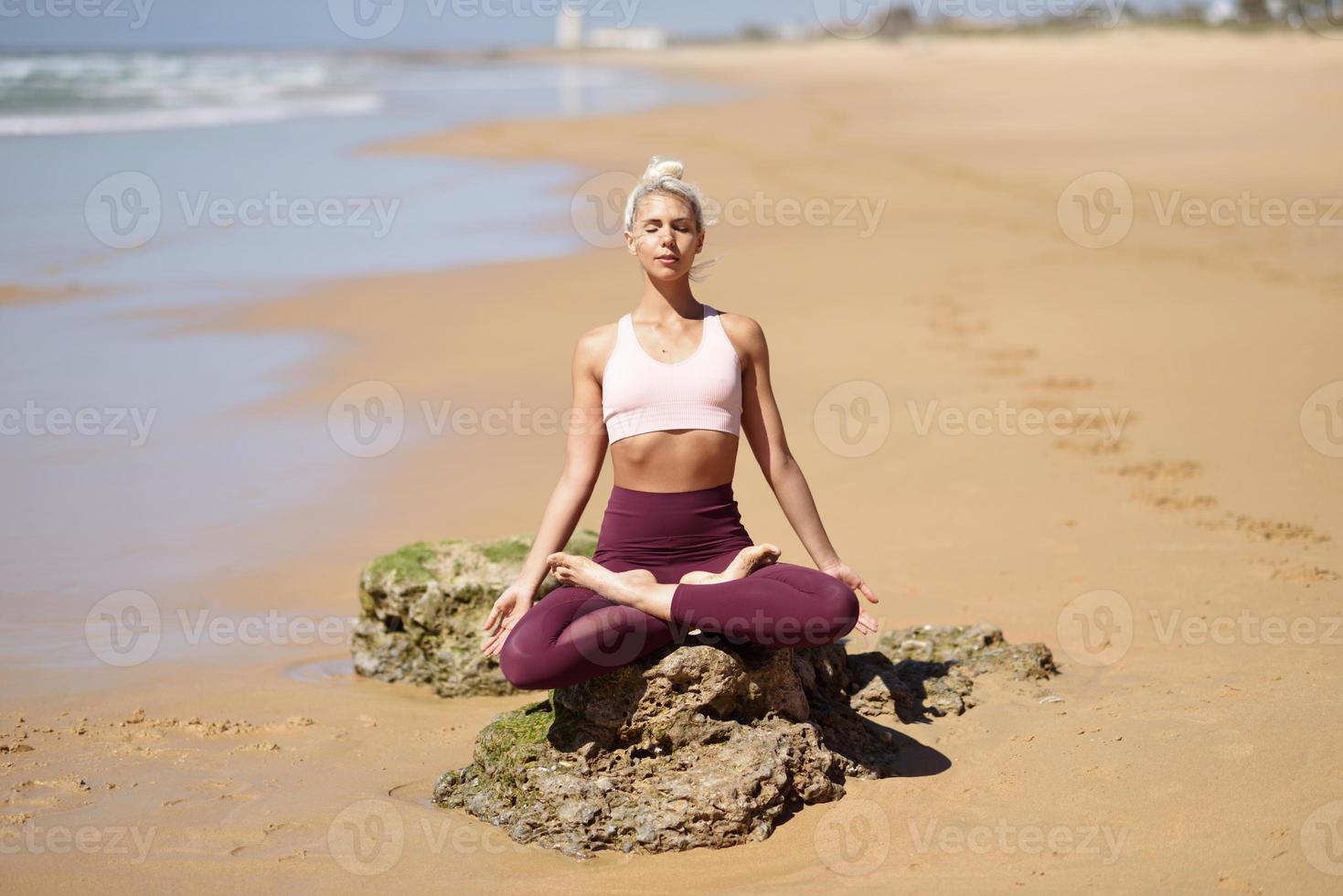 kaukasisk blond kvinna utövar yoga på stranden foto