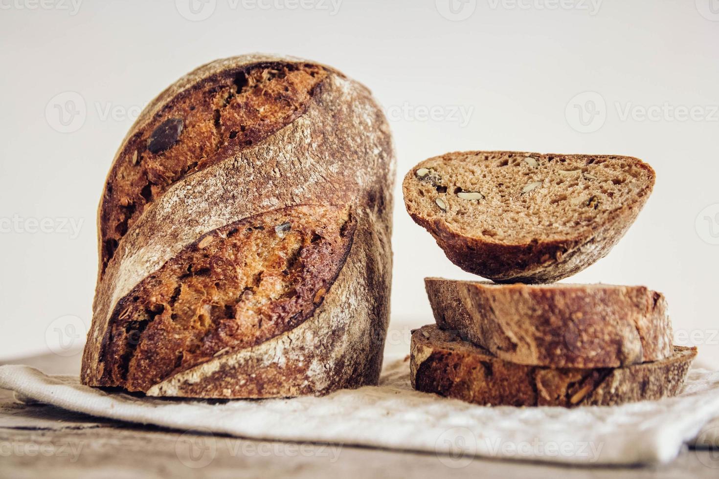 brunt färskt bröd med frön skärs i bitar på gammal träbakgrund foto