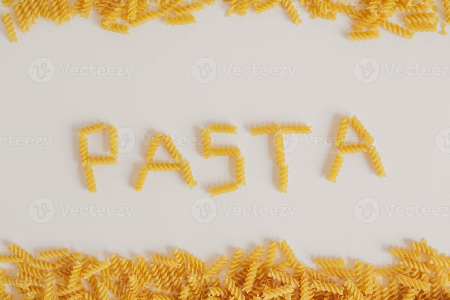 inskription pasta på vit bakgrund och spiral pasta foto