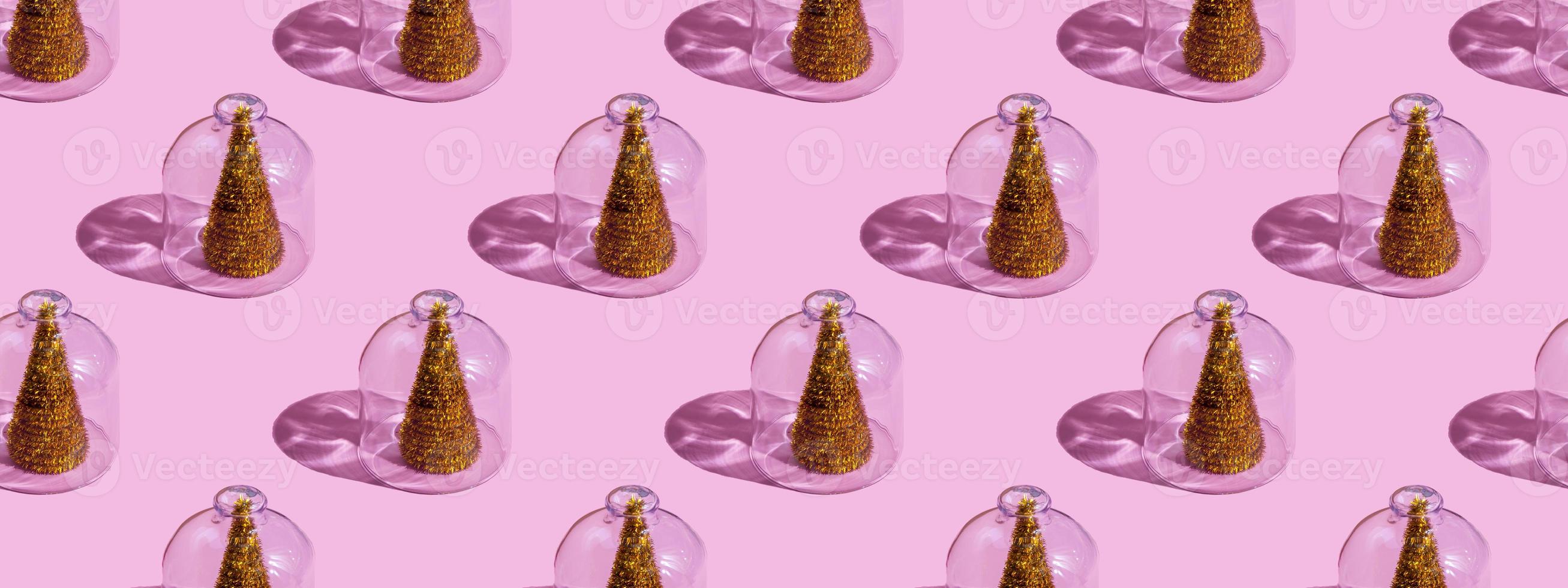 julgran under glas på en rosa bakgrund. julkoncept med kopia utrymme. nyår och jul koncept i karantän. karantänprov. foto