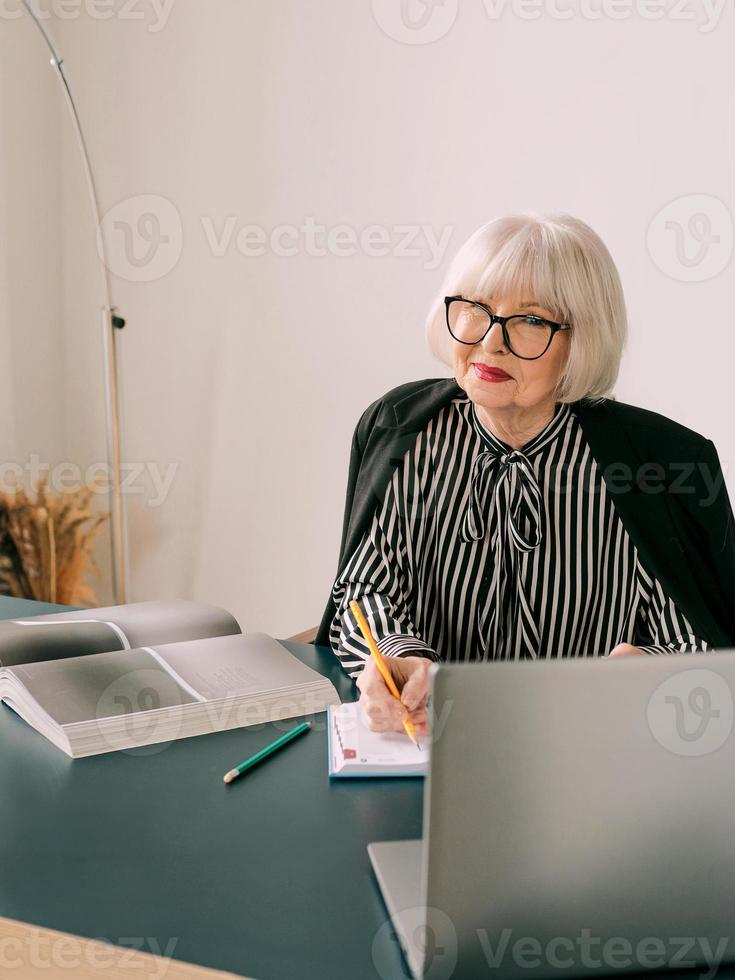 senior vacker grått hår kvinna på hennes kontor. arbete, seniorer, frågor, affärer, erfarenhetskoncept foto