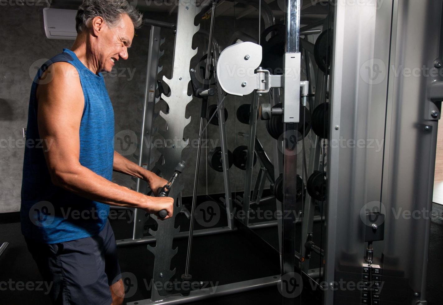 äldre mogen man tränar och gör tricepsförlängningar i gymmet foto