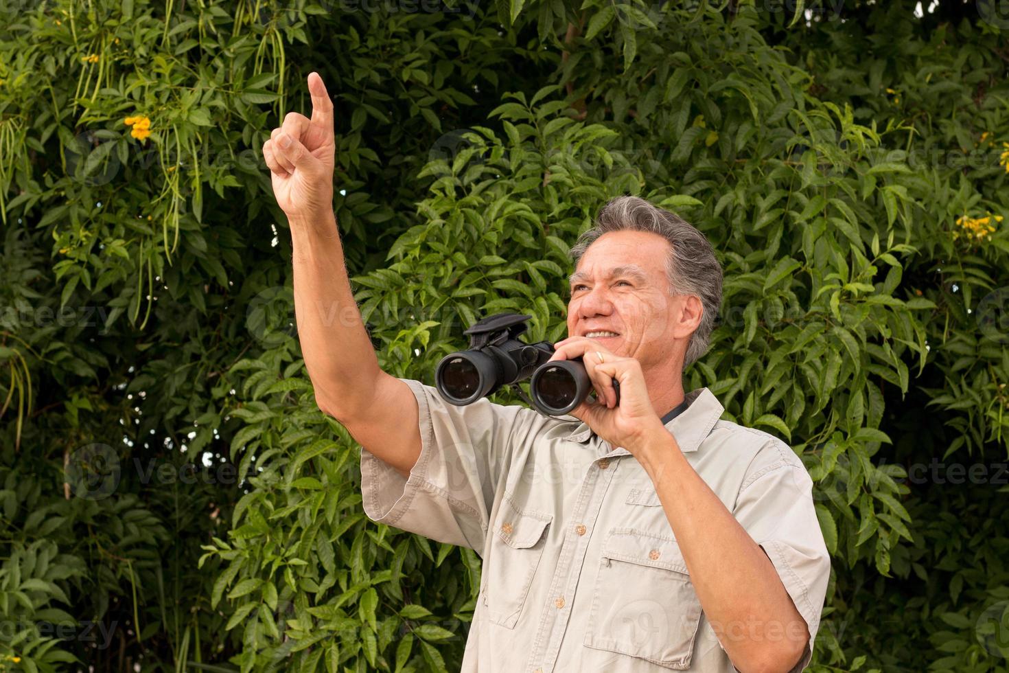 senior man utanför njuter av naturen tittar genom kikare foto