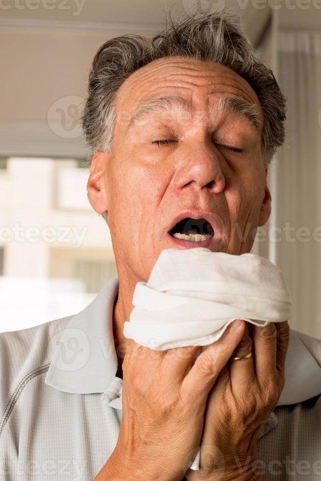 man med influensa som nyser i en näsduk i sitt hus foto