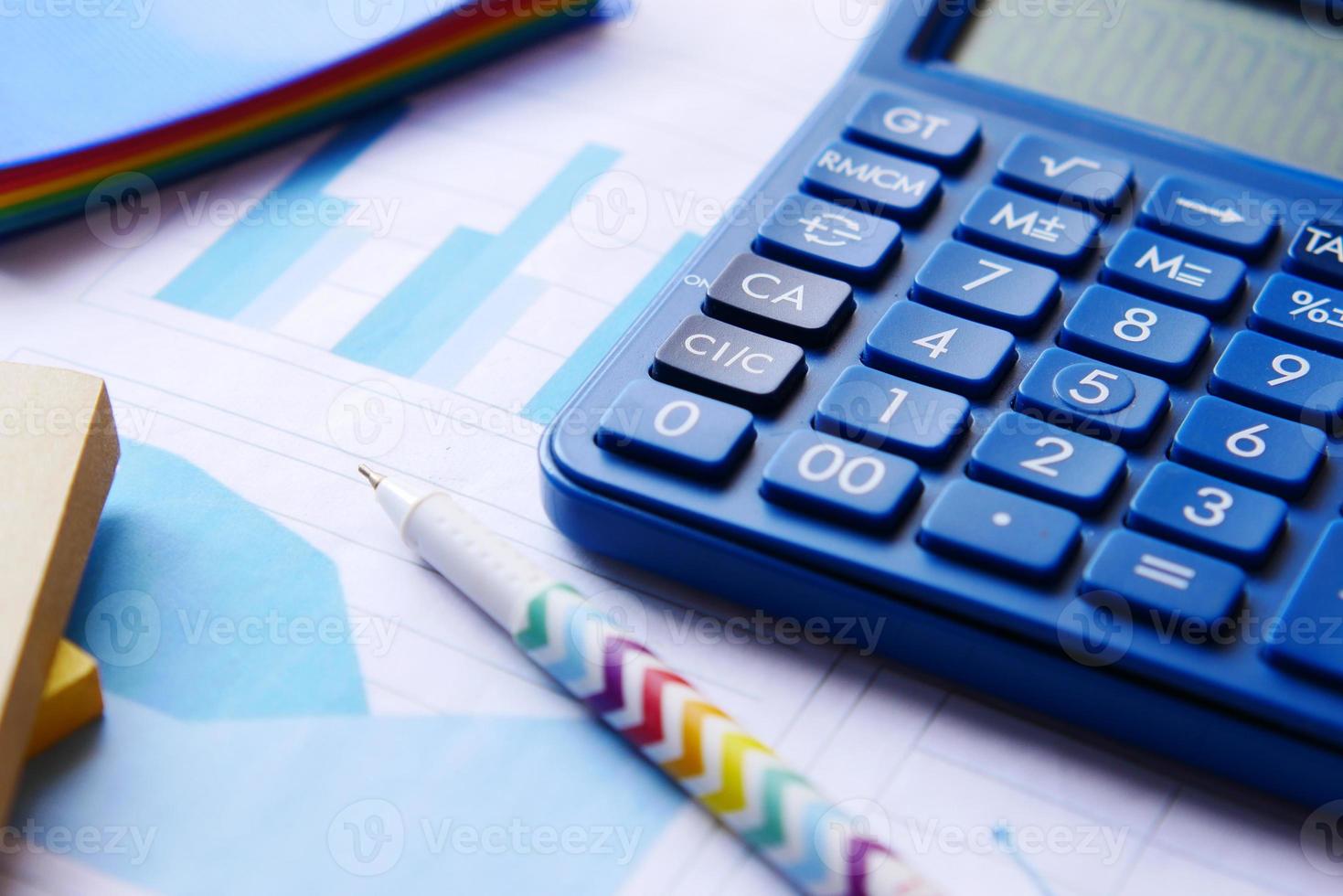 närbild av blå kalkylator och finansiellt diagram på bordet. foto