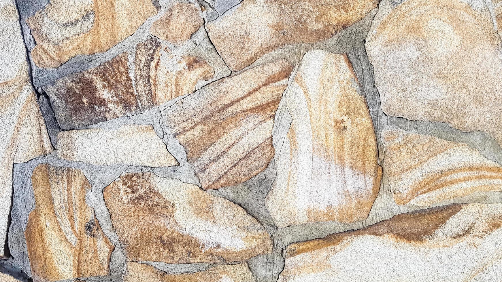 sömlös textur stenvägg. sömlös bakgrund. mönster av modern stildesign dekorativ ojämn sprucken yta av äkta stenvägg med cement. fragment av en vägg från en flisad sten foto