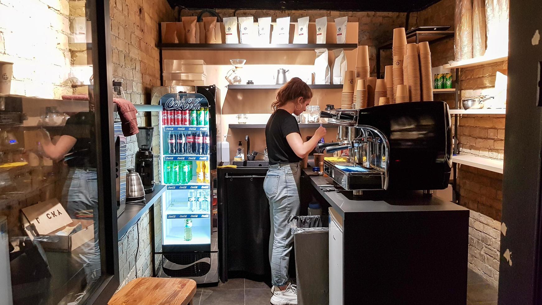 ukraina, kiev - 6 mars 2020. förbered ett arbetsorderkoncept. barista flicka gör kaffe. café och disk med kaffeutrustning, espressomaskin, kaffekvarn, koppar för att göra drycker. foto