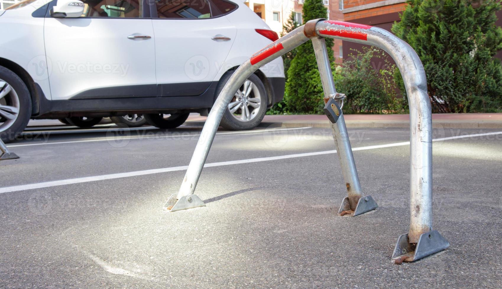 manuell parkeringsbarriär av grå galvaniserad metall med lås. parkeringsbarriär installerad. en hopfällbar barriär hindrar fordonet från att stanna vid denna punkt. foto