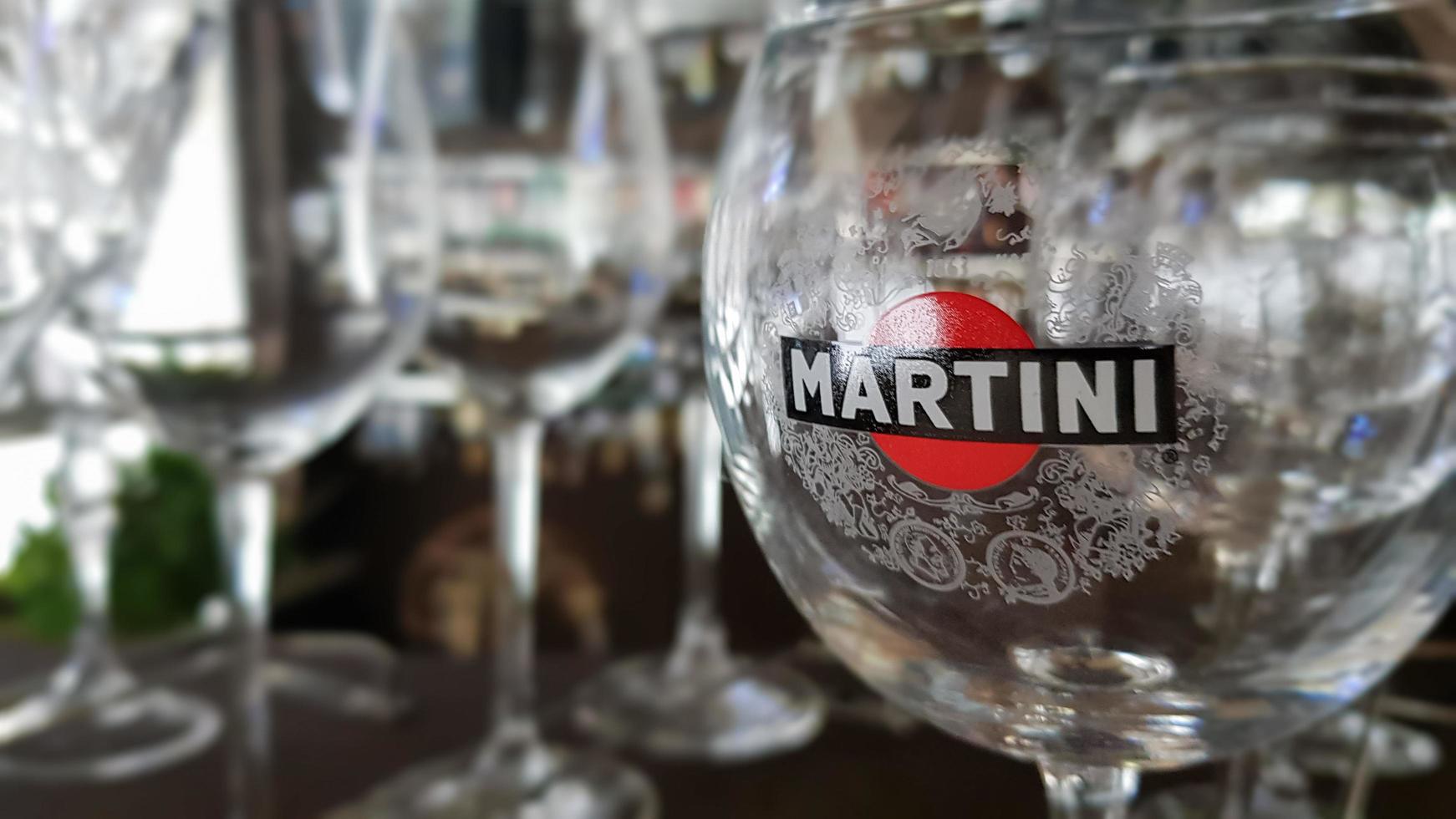 Martiniglas finns i baren. inskriptionen på glaset och logotypen martini klistermärke. ett märke av italiensktillverkade vermouther och mousserande viner. Italien, Turin - 1 oktober 2020. foto