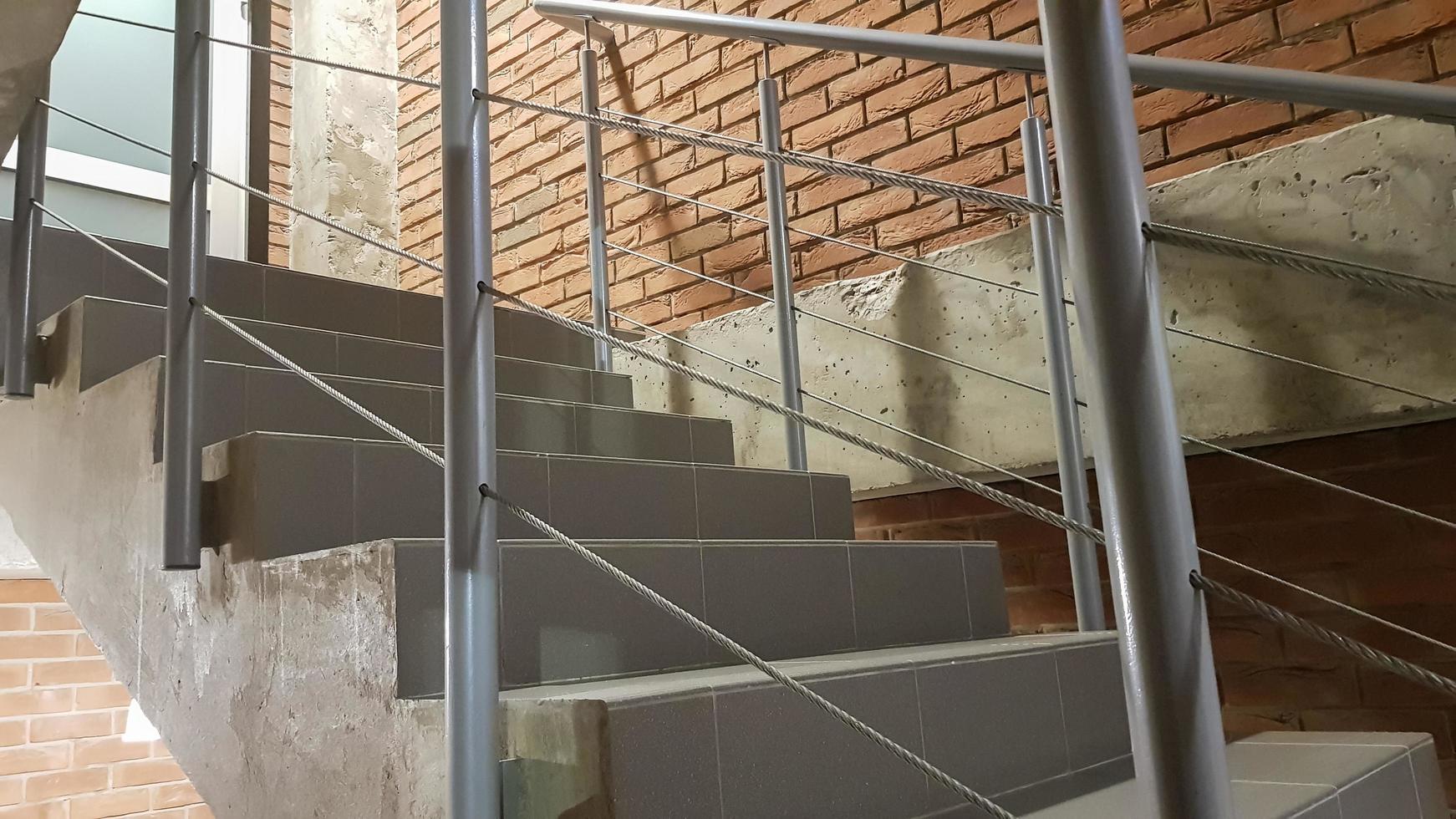rött tegelbyggnad med en modern trappa i loftstil med metallräcke. trappor pryder byggnaden. modernt trapphus. stålräcke. trappa i perspektiv. foto