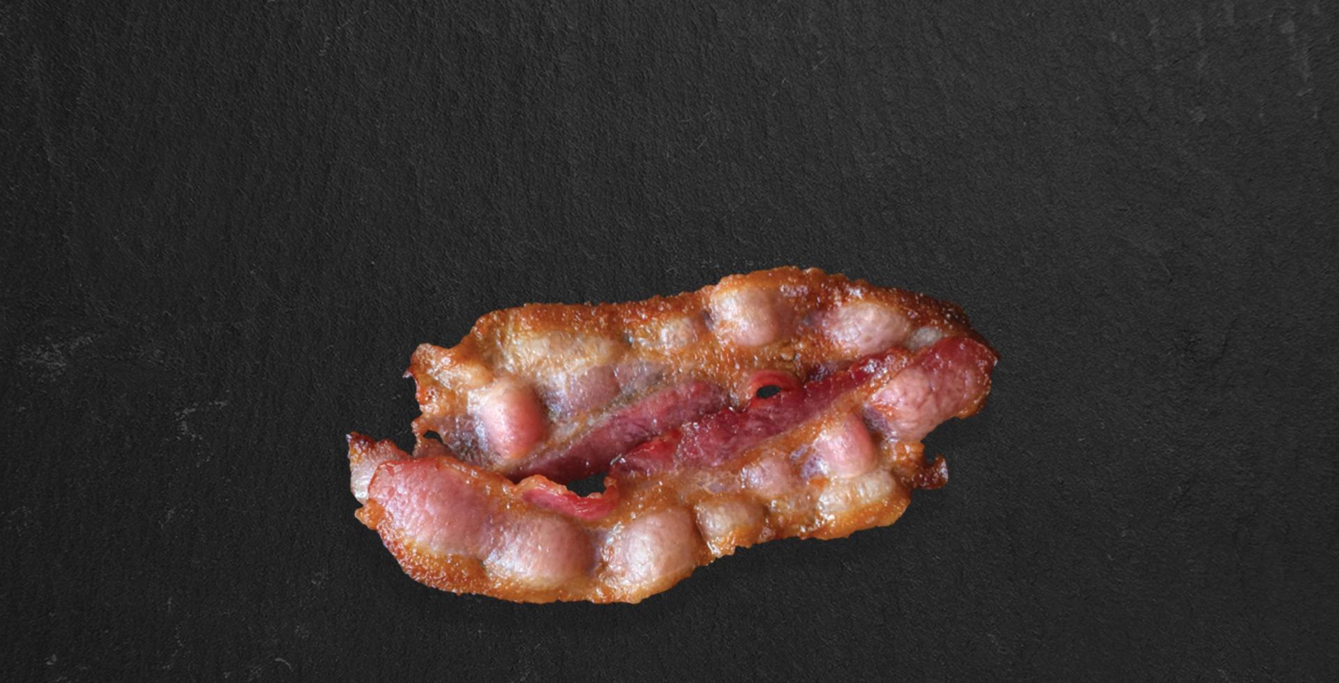 krispiga tjocka skurna rökt baconskivor isolerad på mörk bakgrund, närbild lämplig för matdesignprojekt. foto