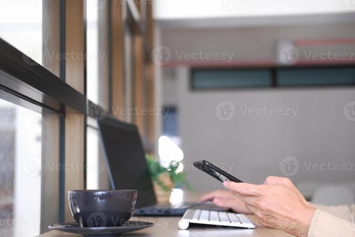 närbild av en mans händer tagna med en smartphone, på kaféet, en man är på sin telefon och skriver meddelanden på sociala medier. foto