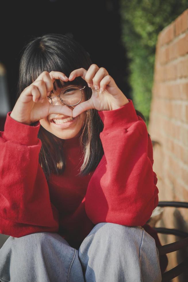 porträtt av glad asiatisk tonåring gör finger som ett hjärta tecken foto