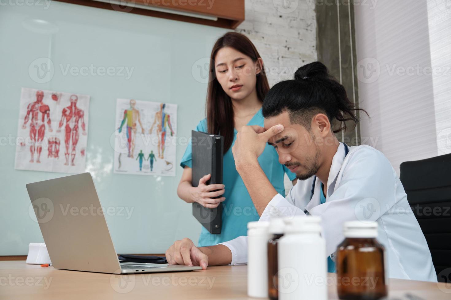 ung kvinnlig kollega uppmuntrar och tröstar manlig doktorpartner av asiatisk etnicitet som är ledsen och stressar på hälso- och sjukvårdsklinikens kontor på sjukhuset. foto