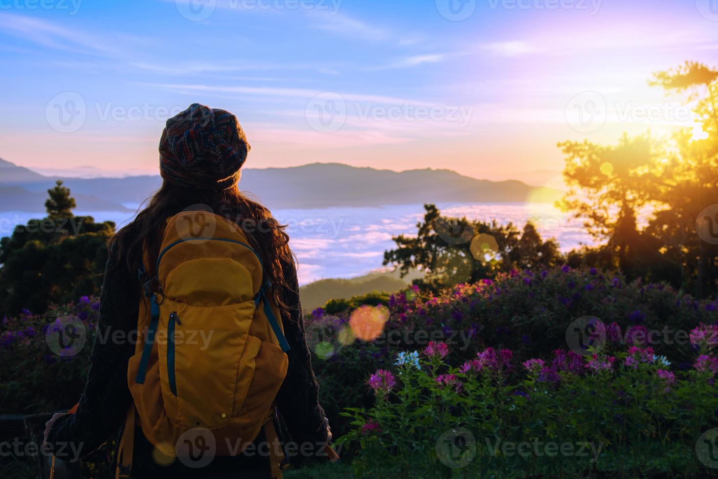 ung kvinna turister med ryggsäckar stående tittar på naturen vacker utsikt över landskapet och dimma på toppen av berget morgon soluppgång. foto